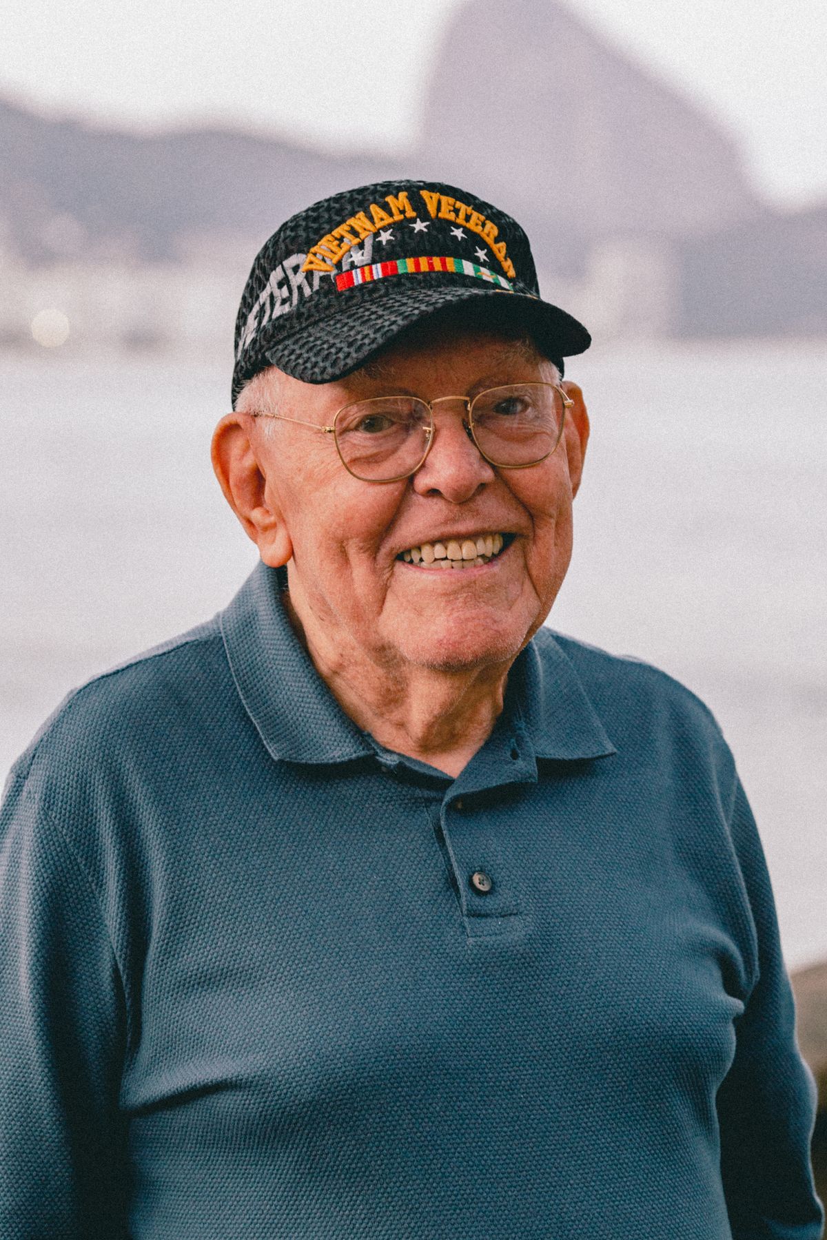 A smiling older U.S. veteran wearing a veteran ball cap